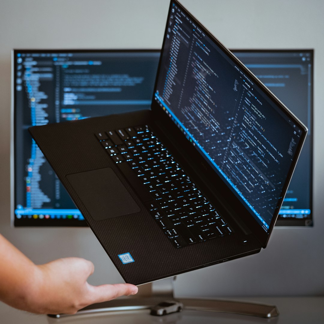 Laptop met regels code, omhooggehouden voor een tweede scherm